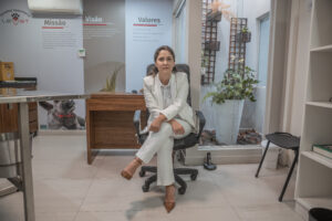 Consultório 1 na LeVet. A imagem mostra um dos consultórios da LeVet, iluminado e com ar condicionado. Há uma mesa para acolhimento do pet e também uma mesa com cadeira, onde está sentada a médica veterinária
