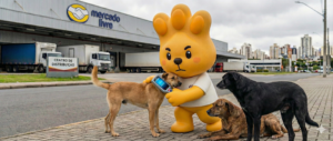 Mascote Zé Patinhas do Hospital Veterinário Levet usando um leitor de microchip em um cachorro, acompanhado de outros dois cães resgatados em frente ao centro de distribuição do Mercado Livre. Alerta sobre microchipagem em Curitiba.